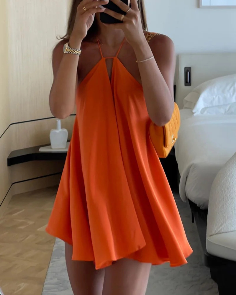 Person wearing an orange dress holding a yellow handbag in a bedroom setting.