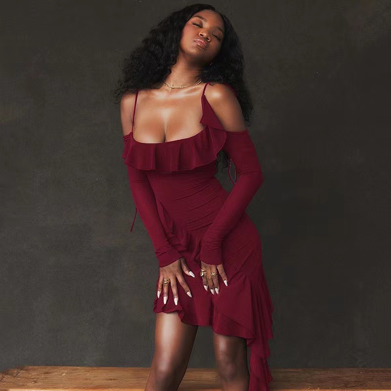 Woman wearing a burgundy dress with ruffled details against a dark background