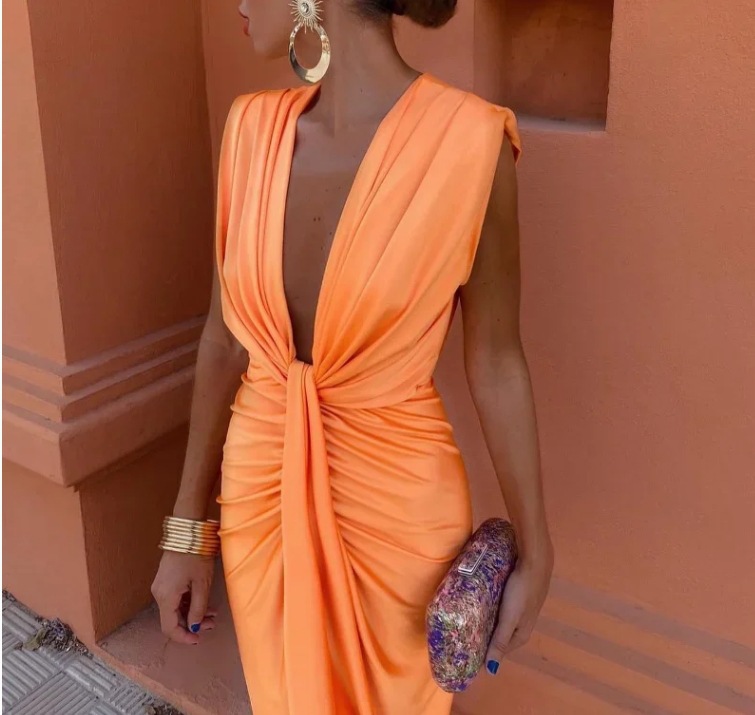 Woman wearing an orange dress with a textured wall background