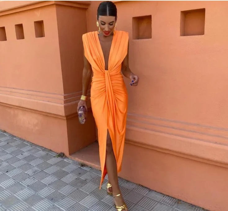 Woman wearing an orange dress with a textured wall background