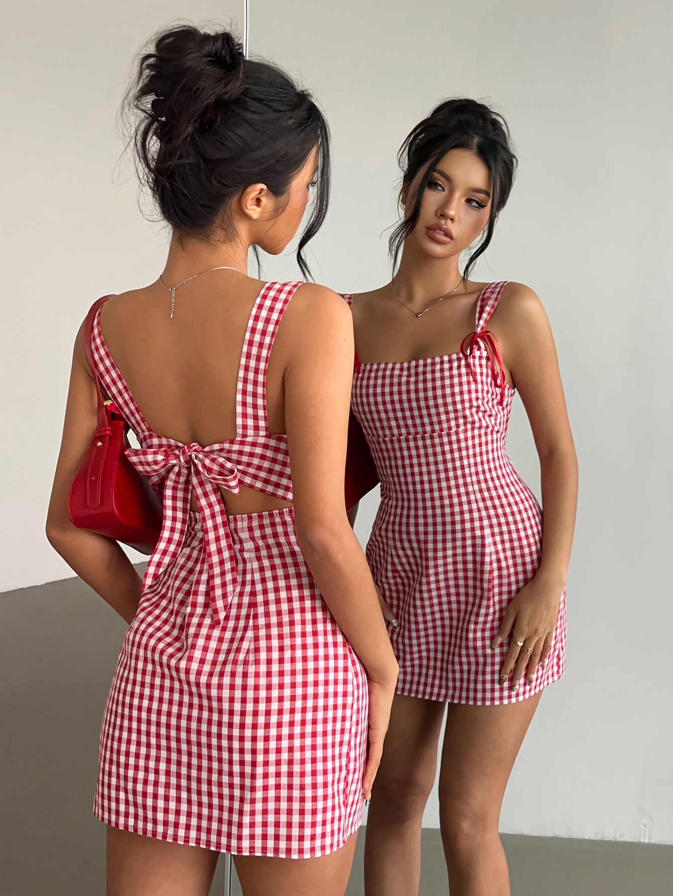 Woman wearing a red and white checkered dress, looking at herself in a mirror.