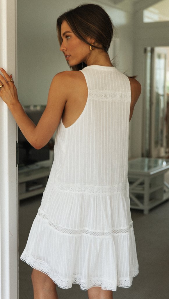 Woman in a white dress standing in a room with neutral decor