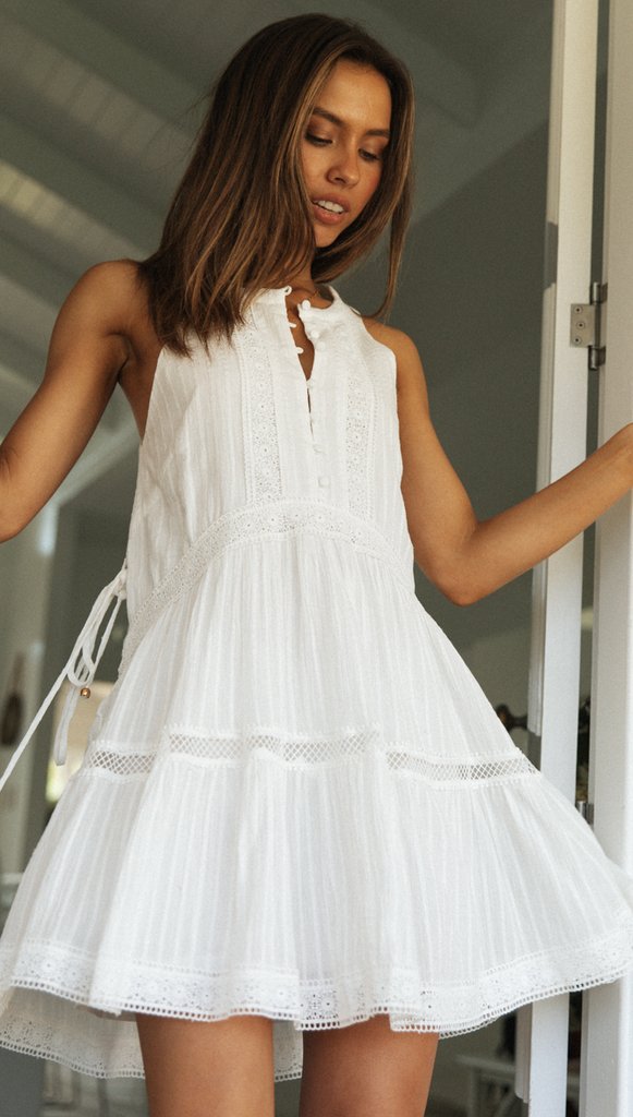 Woman in a white dress standing in a room with a blurred background