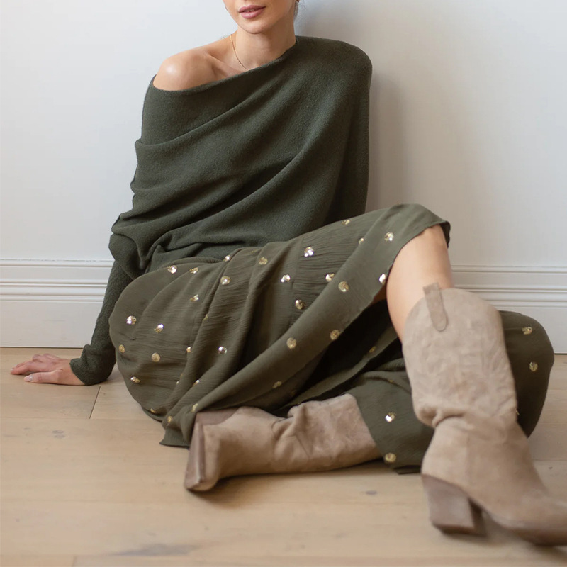Person wearing an off-shoulder green sweater with a plain background