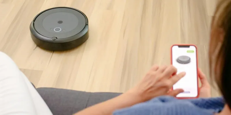 A woman is controlling the robotic vacuum cleaner