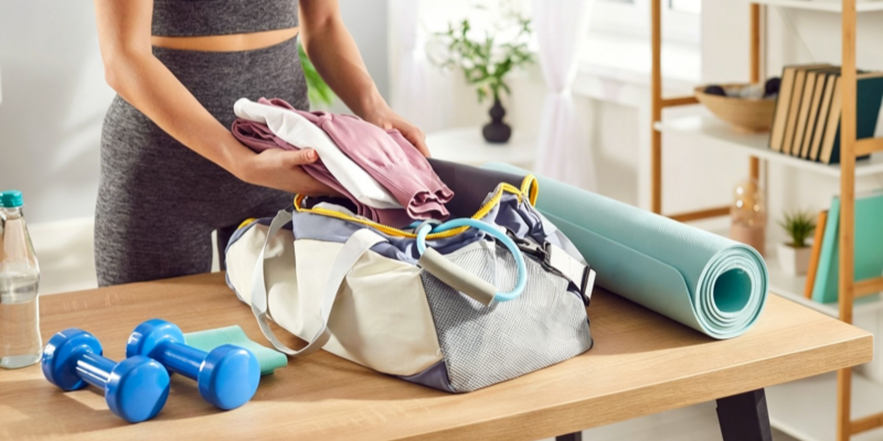 Gym duffel bag with workout clothes yoga mat and blue dumbbells
