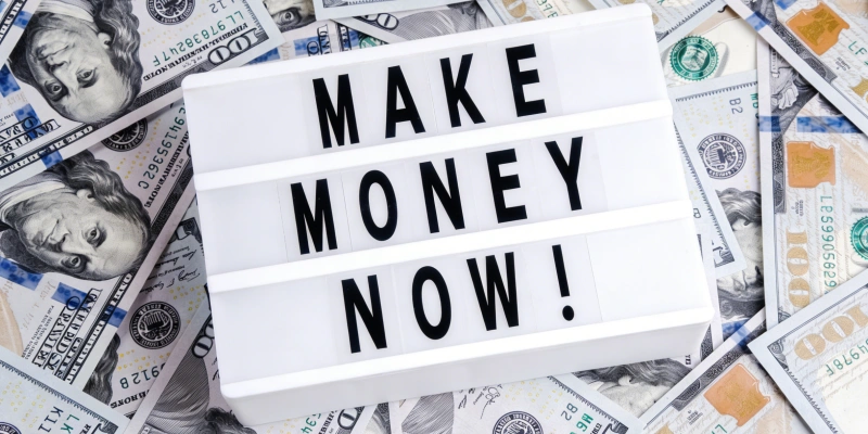 Make money now sign on scattered dollar bills